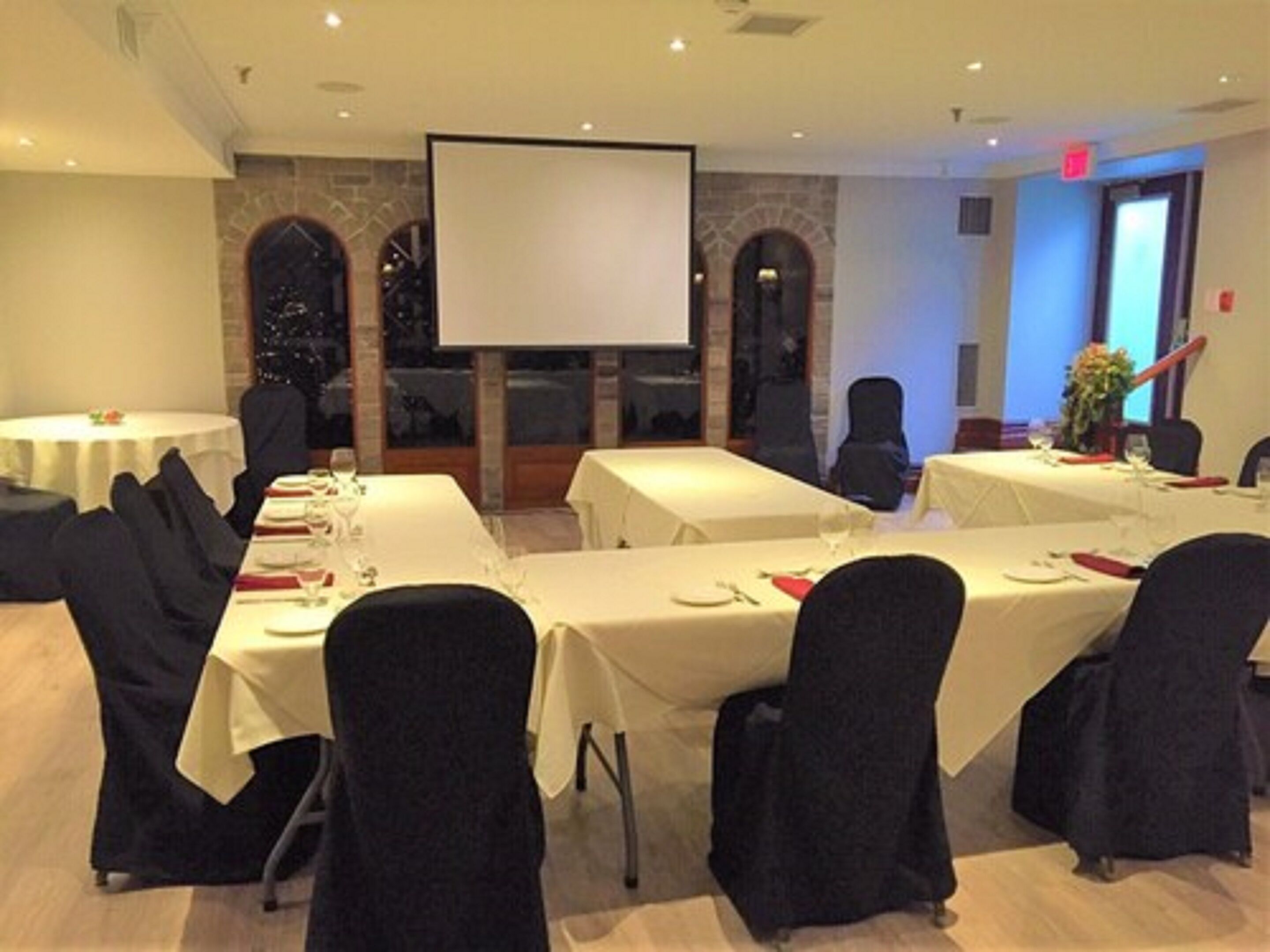 A conference room with tables set for a meeting, a projector screen, and a large window with a view.