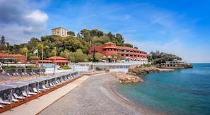A coastal hotel with a beach, a pool area, and a view of the sea.
