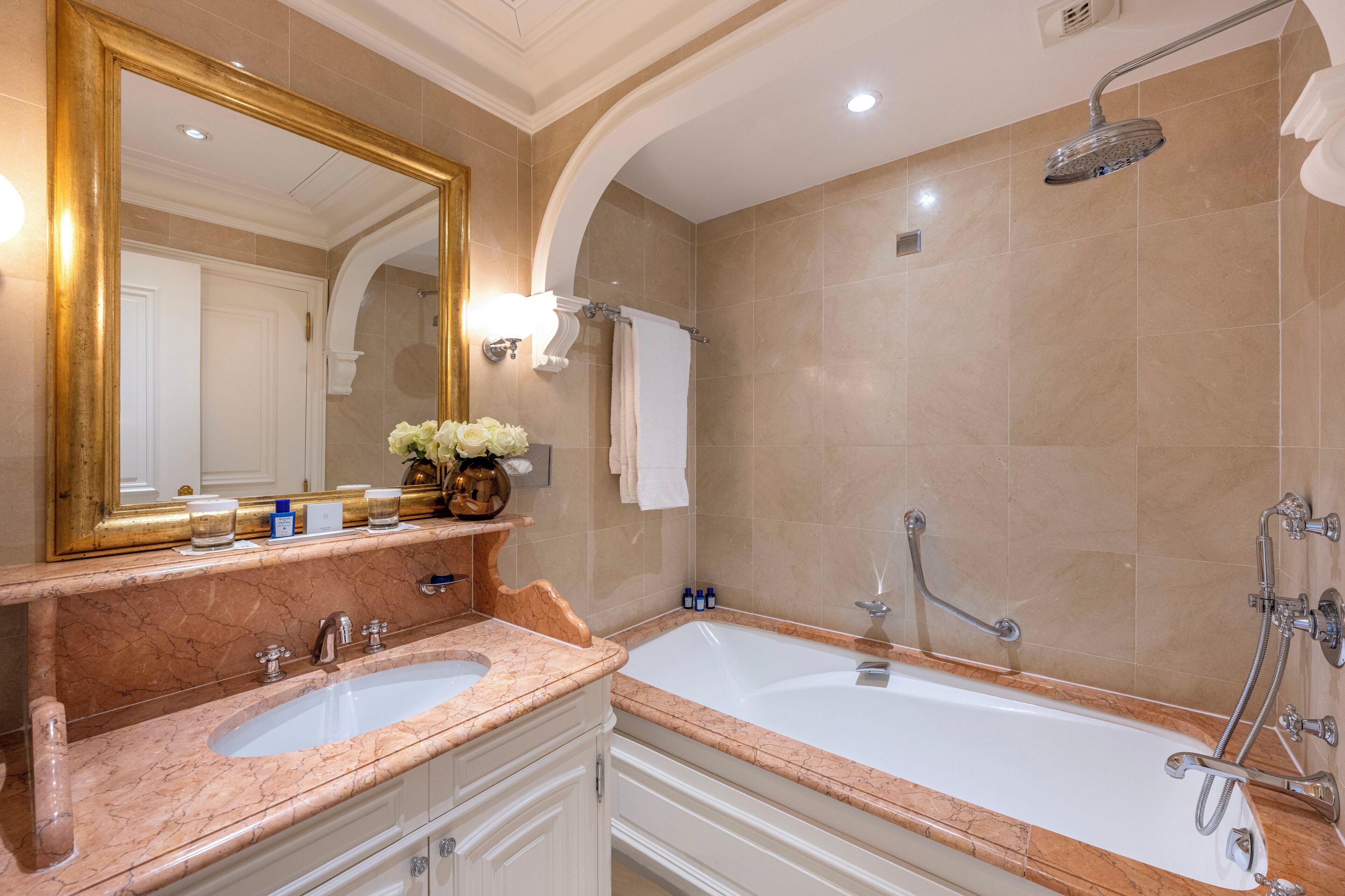 Une salle de bain avec un grand miroir, deux lavabos, une baignoire et une douche.