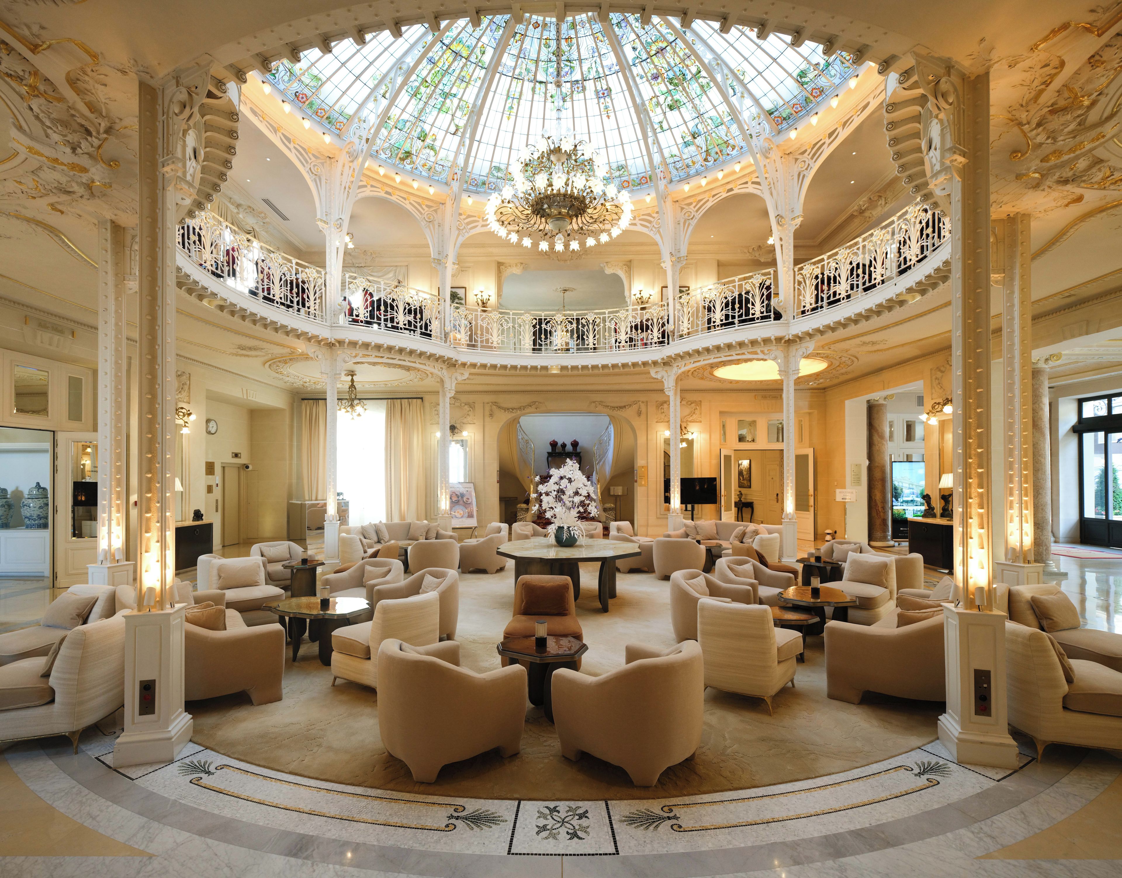 A grand lobby with a high ceiling, ornate columns, and a central chandelier.