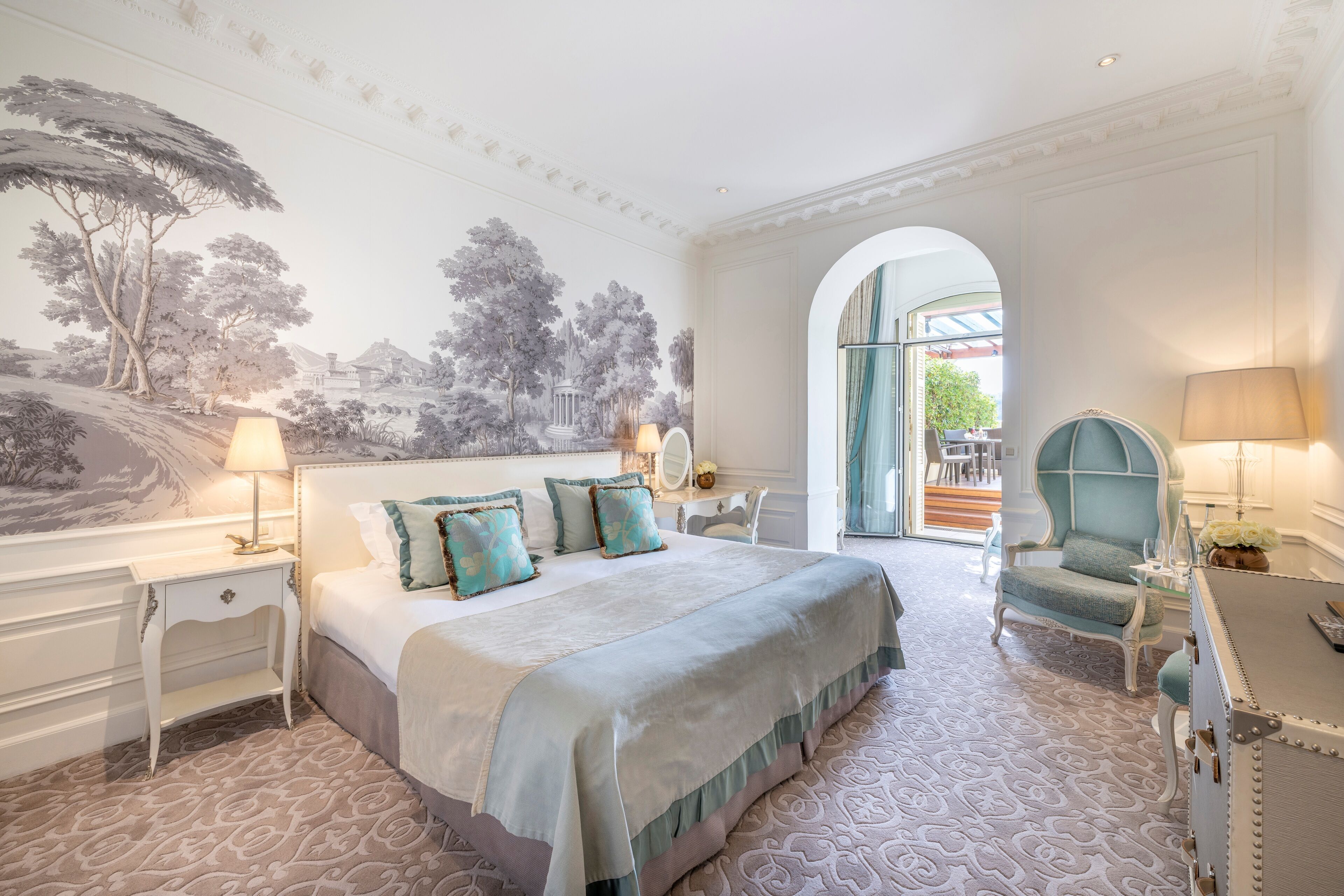 A bedroom with a large bed, a nightstand, a chair, and a lamp.