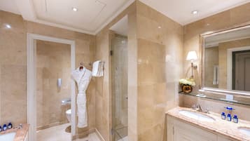 A modern bathroom with a glass shower enclosure, a large mirror, and a marble countertop with two sinks.