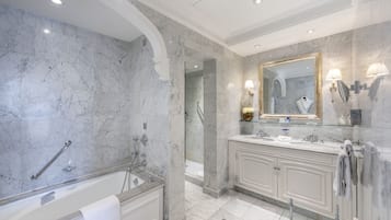 Une salle de bain moderne avec un mur en marbre, une baignoire sur pieds, un grand miroir et un meuble-lavabo doté d’un évier et d’un porte-serviettes.