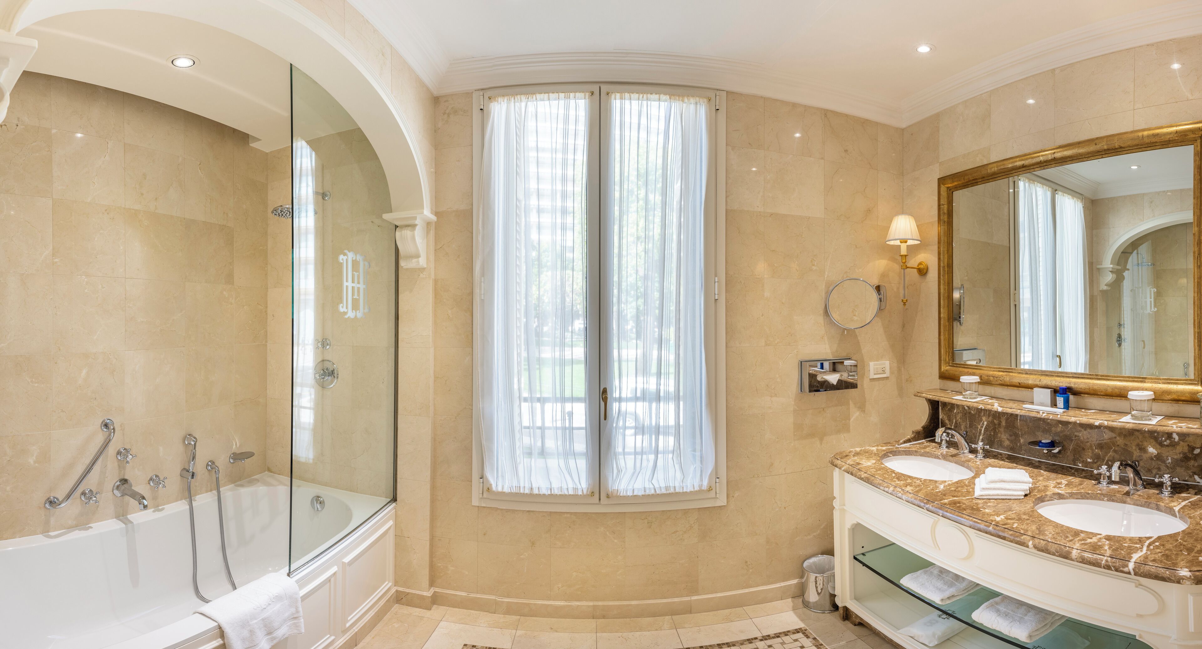 A modern bathroom with a glass-enclosed shower, a large vanity with a marble countertop, and a large mirror.