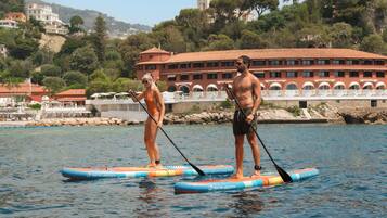 Due persone che fanno paddleboarding in una giornata limpida, con un edificio sullo sfondo.