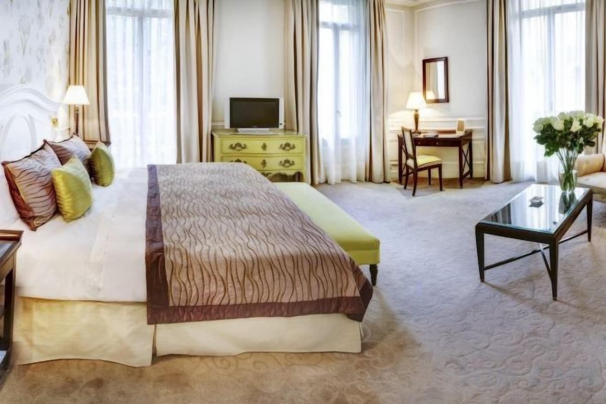A hotel room with a large bed, a desk, a television, and a view of the outdoors.