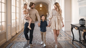 Una familia camina por un pasillo de arquitectura ornamentada, con candelabros y un suelo con diseño.