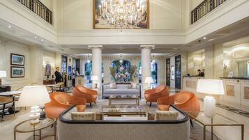 A spacious lobby with a central seating area, a chandelier, and a reception desk.