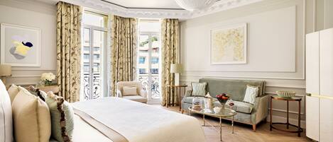Habitación de hotel con una cama grande, un sofá, una mesita de centro y vistas al exterior.