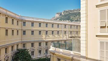 Un immeuble à plusieurs étages doté d’un balcon incurvé, une rue en contrebas et une montagne en arrière-plan.