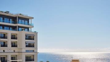 A multi-story hotel with balconies overlooking a coastal view.