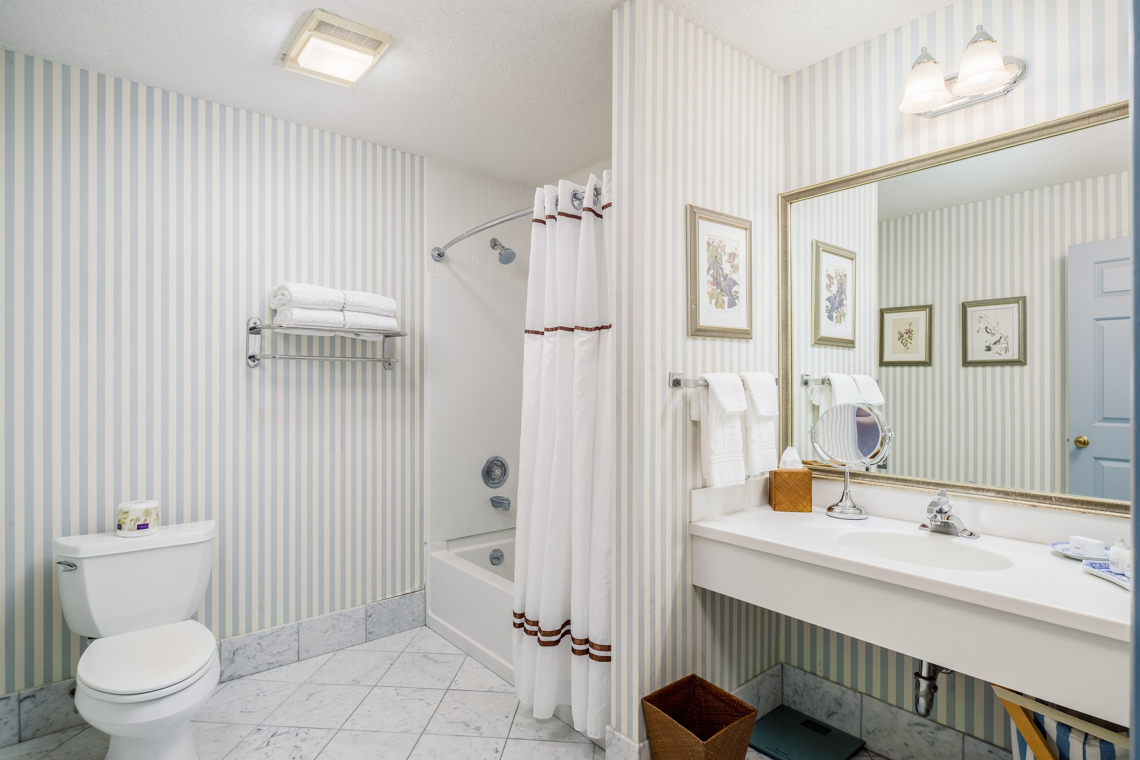 A bathroom with a toilet, shower, and sink.