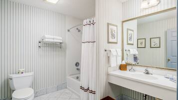 A bathroom with a toilet, shower, and sink.