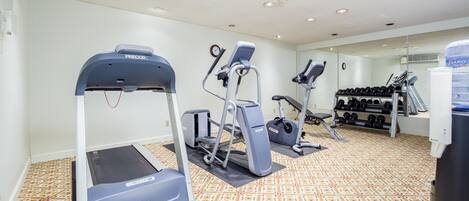A gym with treadmills, elliptical machines, and a rack of dumbbells.