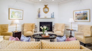 Une pièce bien éclairée, dotée d’une cheminée, de deux fauteuils, d’un canapé et d’une table basse.