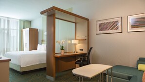Una habitación de hotel con una cama, un escritorio, una silla, una mesita y dos cuadros enmarcados en la pared.