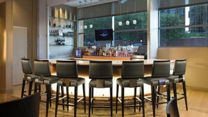 Una zona de bar con una barra alargada, varios taburetes y una pantalla de televisión.
