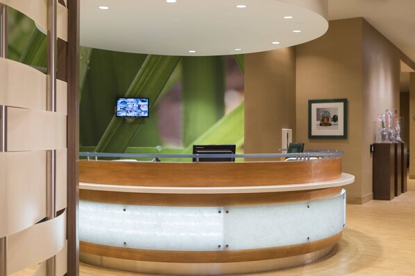 A reception desk with a curved design, a mounted television, and a framed picture on the wall.