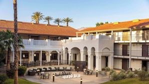 A courtyard with outdoor seating, palm trees, and a chessboard.