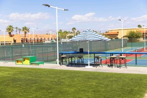 Una cancha de tenis con zona de estar, una red y una valla.