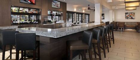 A bar area with a long counter, multiple seating options, and a television displaying a racing event.