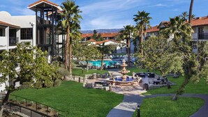 A resort with a pool, outdoor seating, and palm trees.