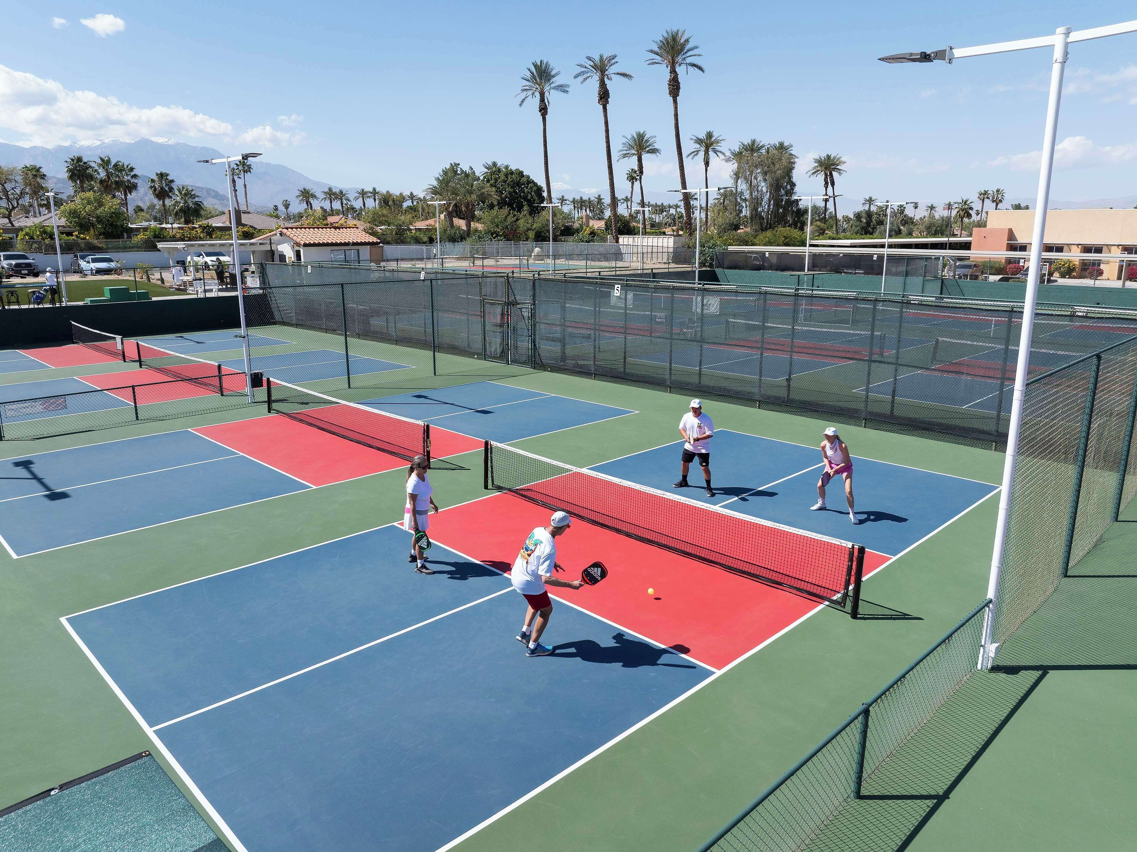 A tennis court with multiple courts, a net, and players.