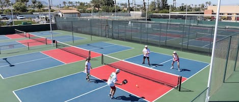 Canchas de tenis múltiples, una red y jugadores.