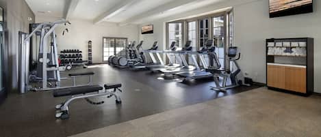 A modern gym with treadmills, elliptical machines, and weightlifting equipment.