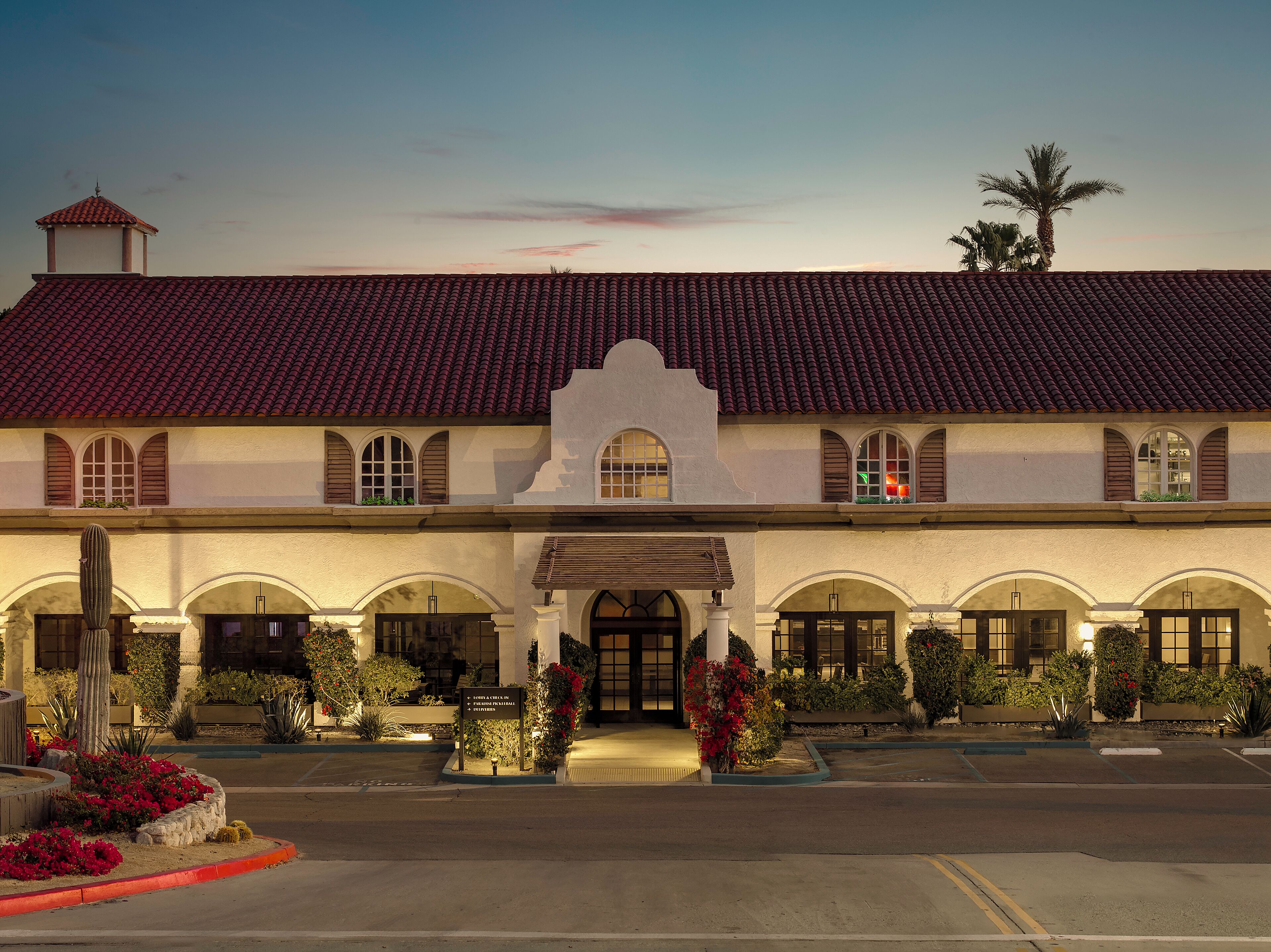 Um hotel com telhado de telhas vermelhas, janelas em arco e uma entrada central com arco decorativo.