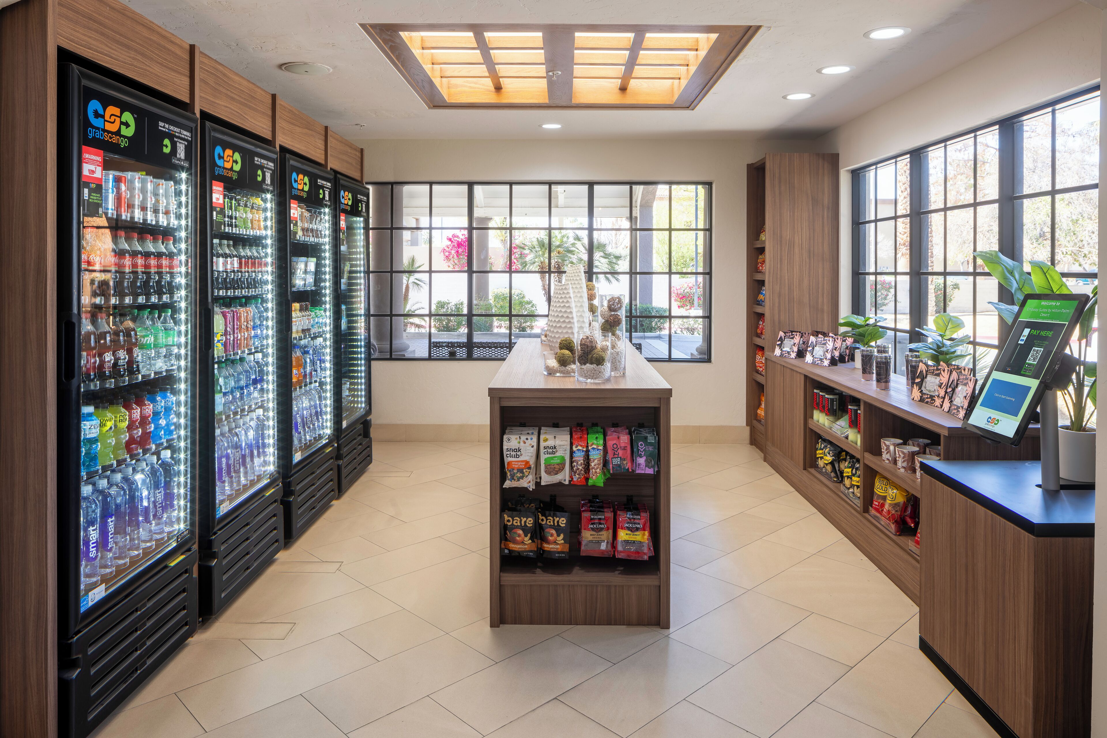 A clean, well-lit room with vending machines, a small counter with a digital kiosk, and large windows offering a view of the outdoors.