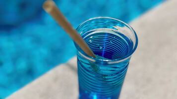 A clear blue plastic cup with a straw on a tiled surface near a pool.