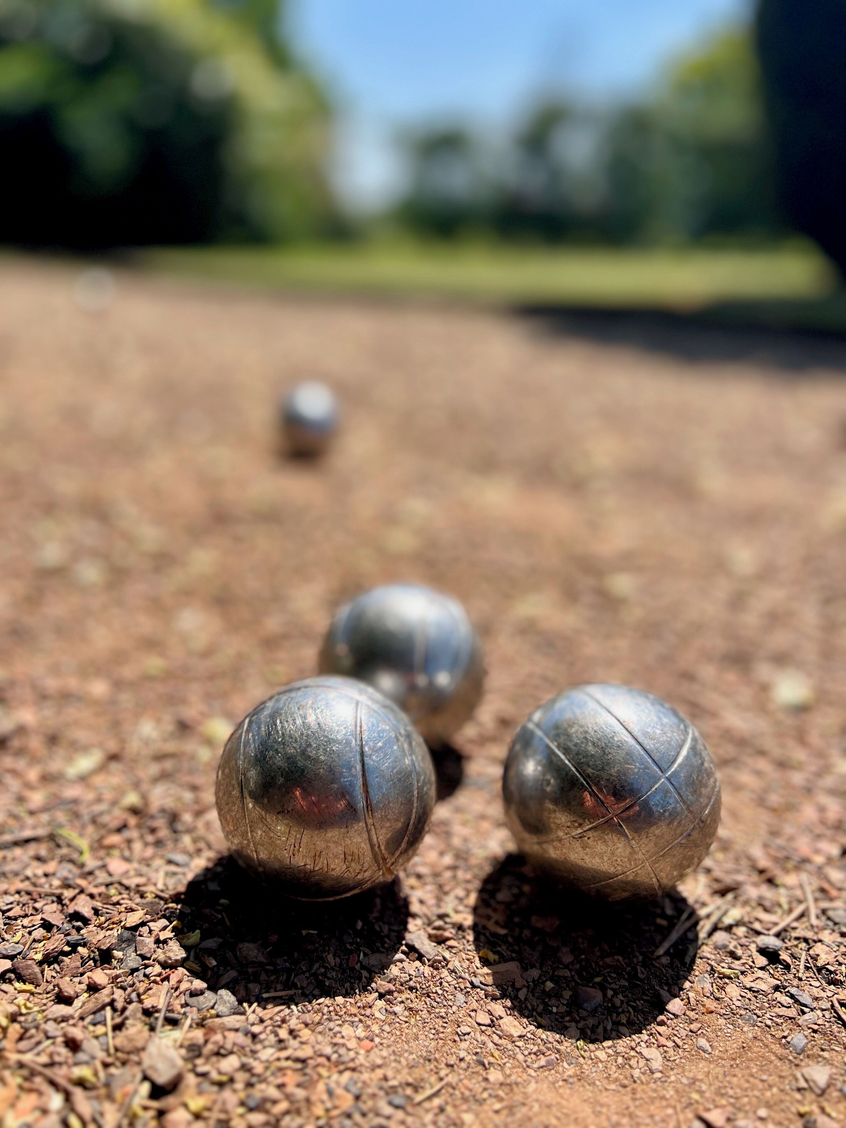 A close-up of four metallic balls on a gravel surface.