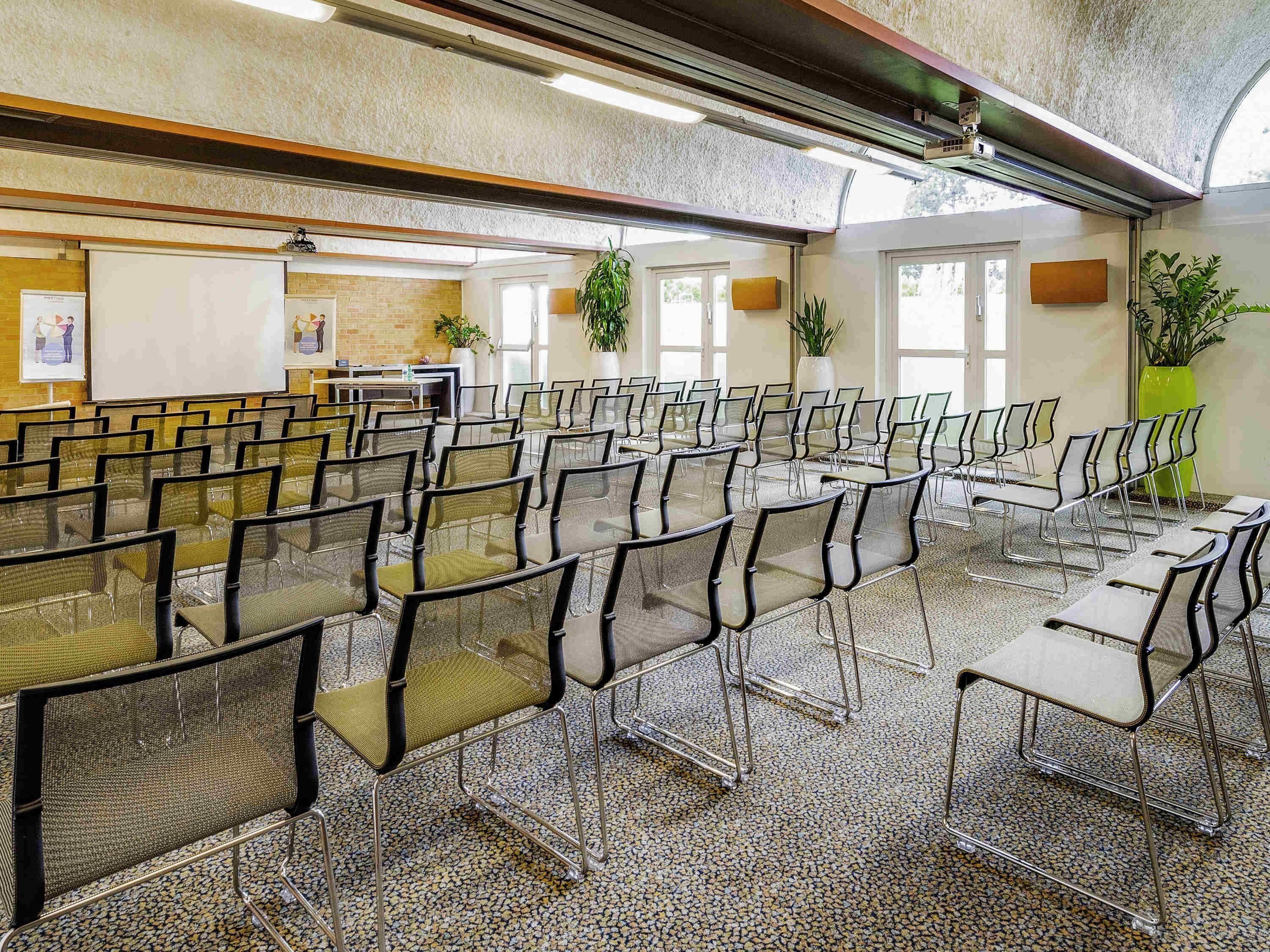 A conference room with rows of chairs and tables, a whiteboard, and large windows.
