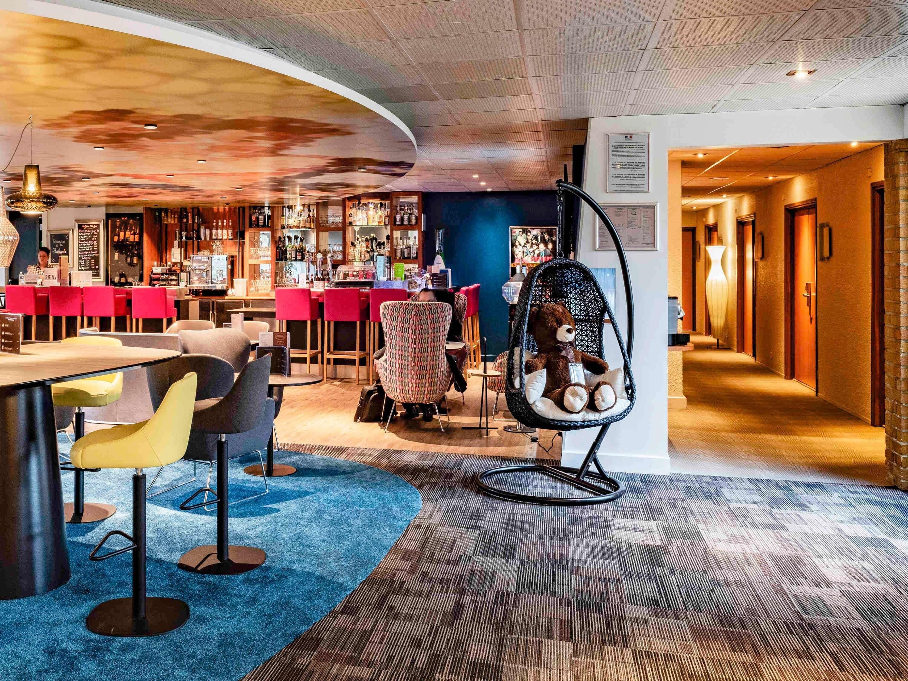Un área de bar moderna con asientos, una silla colgante y una barra.