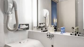 Une salle de bain moderne avec un grand lavabo, un sèche-cheveux et des articles de toilette posés sur le comptoir.