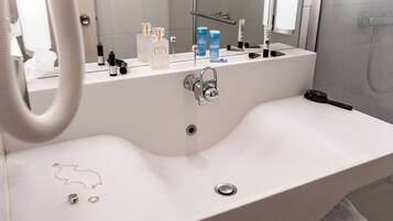 Een moderne badkamer met een wit wastafelmeubel, een spiegel en diverse toiletartikelen op het aanrecht.