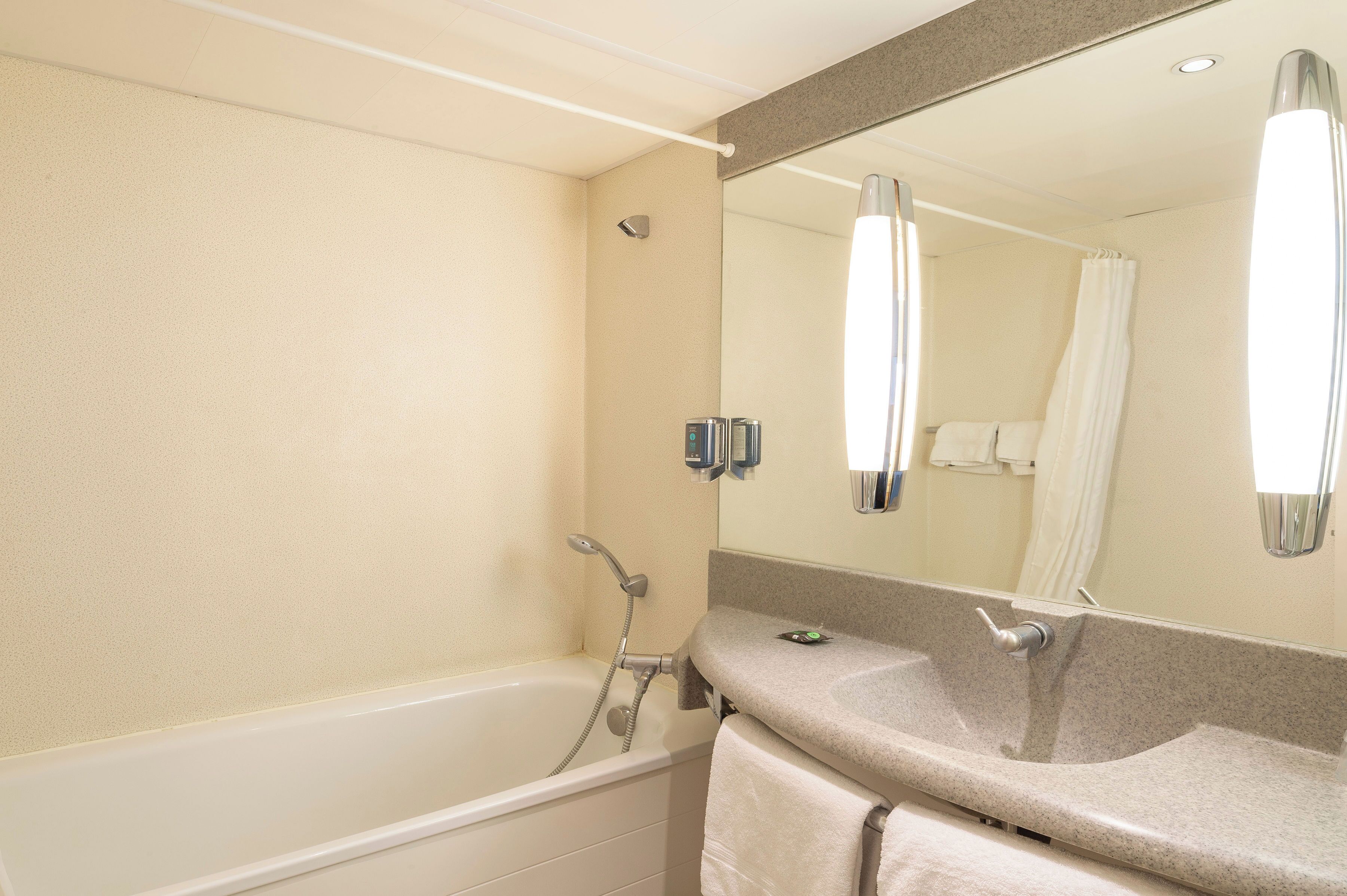 A bathroom with a bathtub, a sink, a mirror, and a shower.