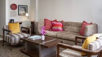 A living room with a sofa, two armchairs, a coffee table, and decorative pillows.