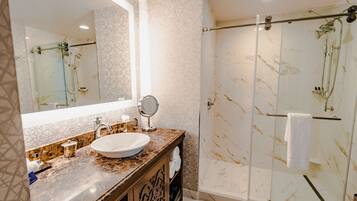 A bathroom with a marble sink, a large mirror, a glass-enclosed shower, and a towel rack.