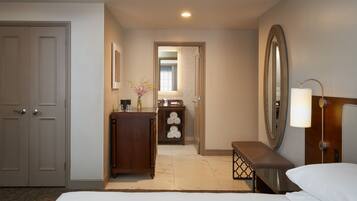 A hotel room with a bed, a desk, a dresser, a mirror, and a bathroom visible through an open door.