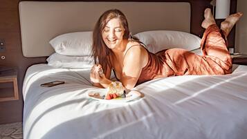 A person lying on a bed with a plate of food and a smartphone.