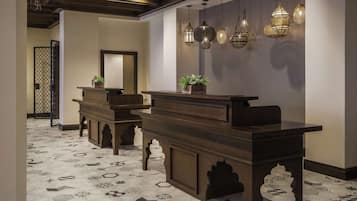 A reception area with a wooden reception desk, potted plants, and hanging decorative lights.