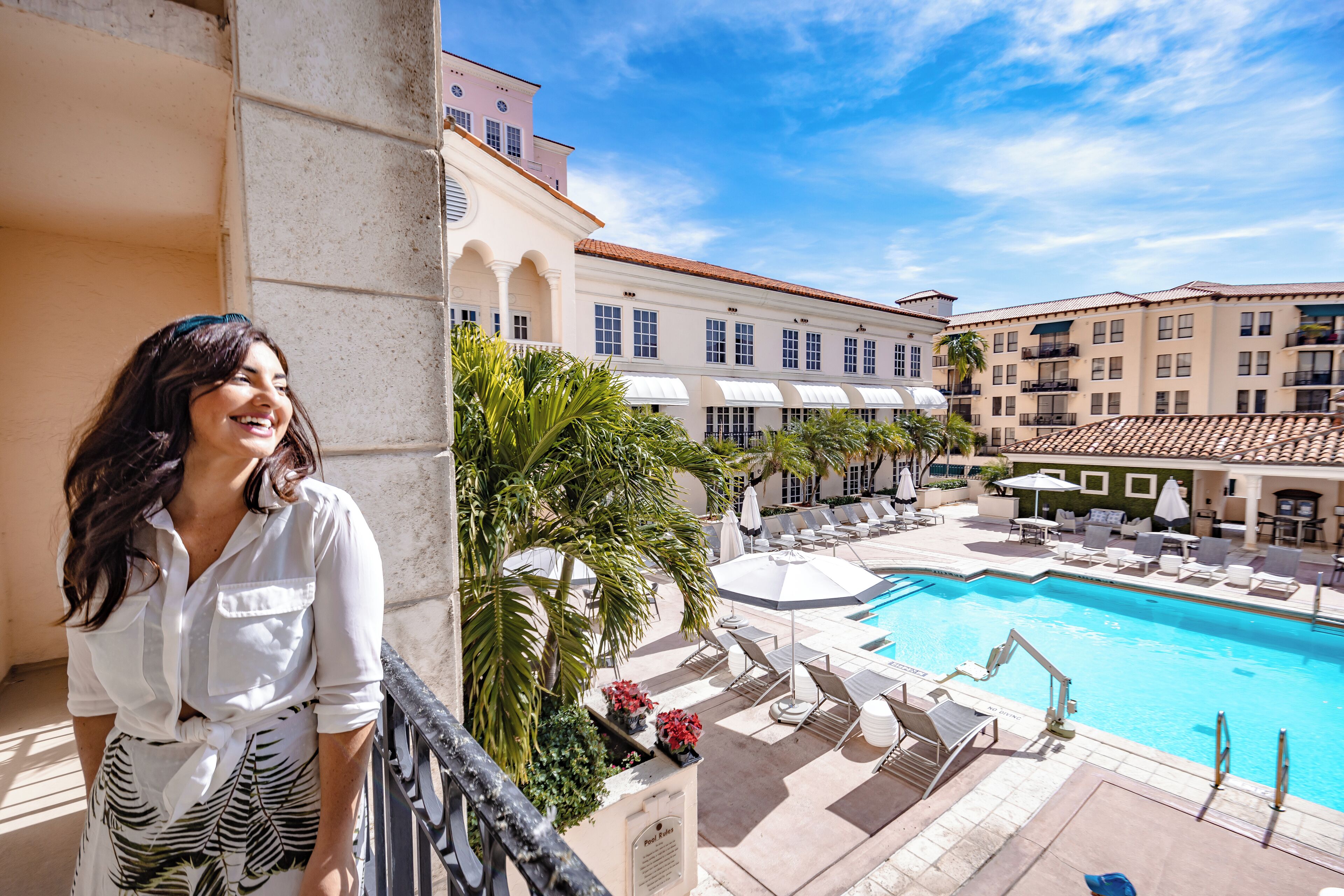 A hotel with a pool area, including lounge chairs and umbrellas.