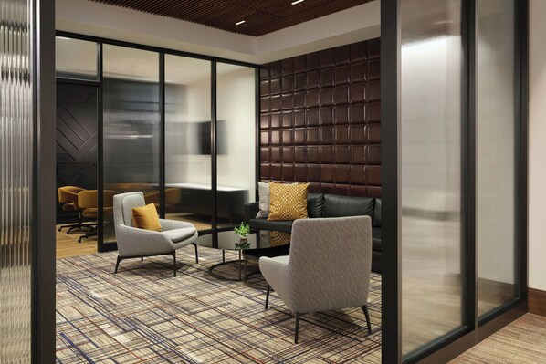 A modern lounge area with a sofa, two armchairs, a coffee table, and a patterned carpet.