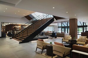 A spacious lobby with a modern staircase, comfortable seating areas, and large windows. - Sheraton Denver West Hotel (Lakewood)