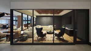 Una sala de estar moderna con un sofá, dos sillones, una mesa de centro y un sistema de sonido integrado en la pared.