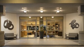 A modern hotel lobby with a reception desk, seating area, and a large potted plant. - Costa Mesa Marriott (Costa Mesa)
