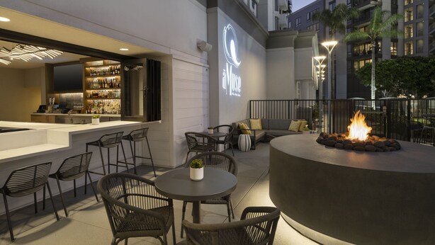 An outdoor bar area with seating, a fire pit, and a bar stocked with bottles. - Costa Mesa Marriott (Costa Mesa)