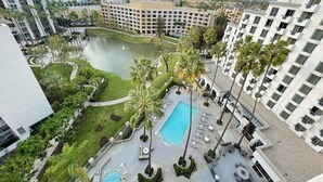 A hotel with a swimming pool, palm trees, and a view of the surrounding cityscape. - Costa Mesa Marriott (Costa Mesa)